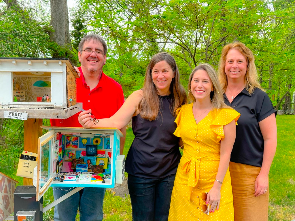 Teachers standing beside miniature art galleries for display.