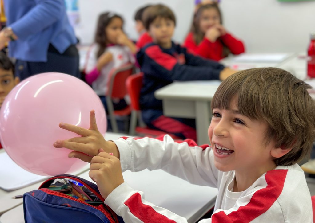 A smiling child with pink balloon.